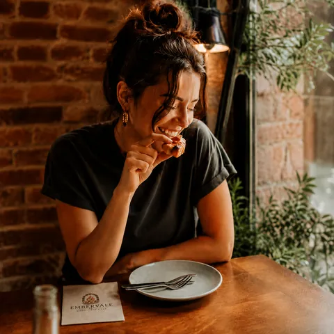 A generated Embervale visual: a guest enjoying pizza in the dining room